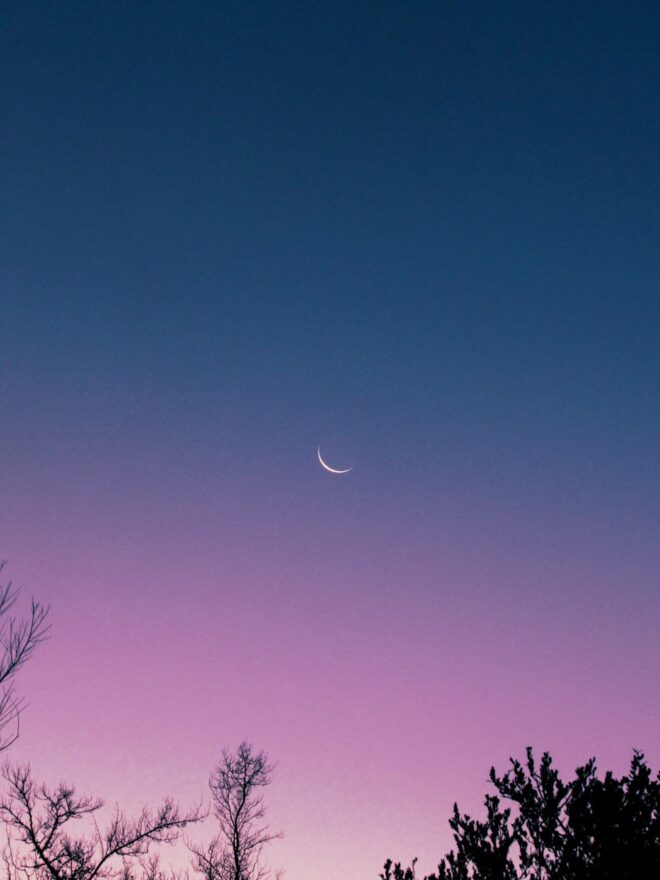a crescent moon on blue sky at twilight